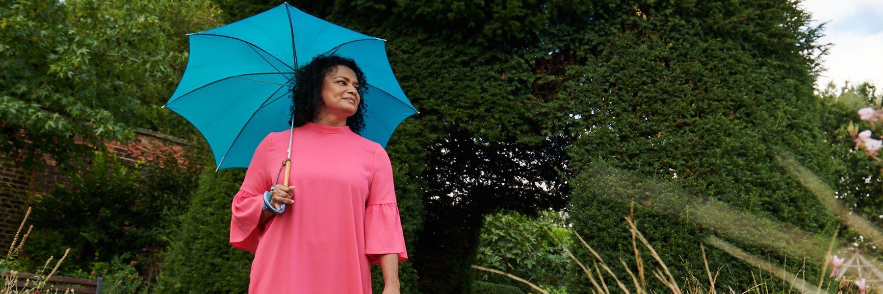 A smiling woman holding a pink umbrella