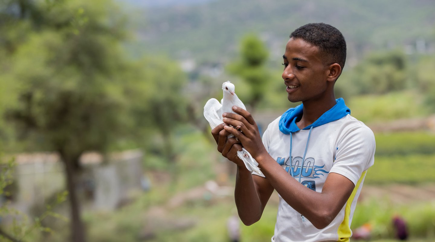 Munadhel, a university student from Yemen, holds a white dove.