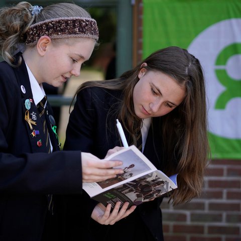 Two girls look at a book together at their secondary school in the UK