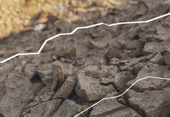 Close-up of dry, cracked earth with white contour lines overlaid, highlighting the uneven surface and texture of the ground.