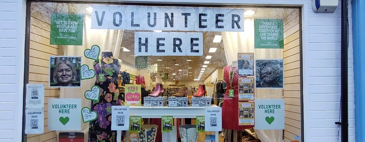 An Oxfam shop window with posters reading 'Volunteer here'