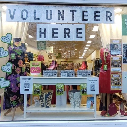 An Oxfam shop window with posters reading 'Volunteer here'