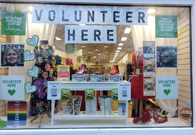 An Oxfam shop window with posters reading 'Volunteer here'