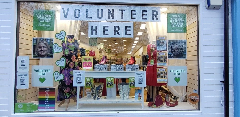 An Oxfam shop window with posters reading 'Volunteer here'