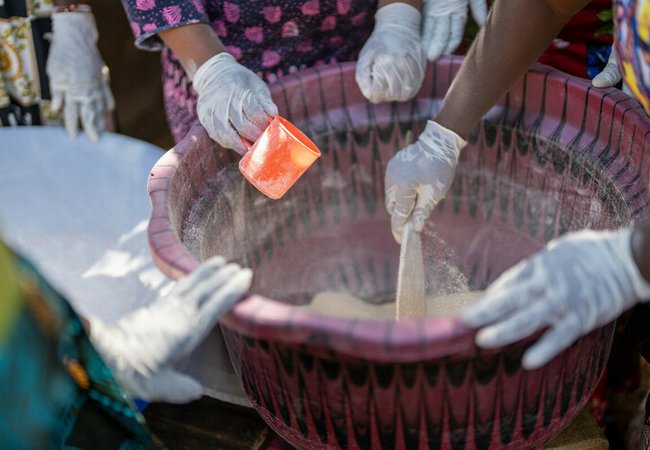 Magdalene Bangura, the leader of Female Pastors Network (FEMINET) leads the gari making process at her home in Sierra Leone.