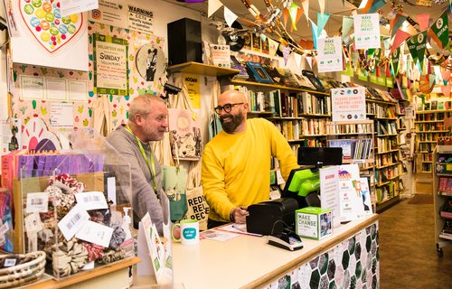 Volunteer Jeff and Shop Manager Scott behind the counter in the Kensington Garden's Oxfam Bookshop in Brighton