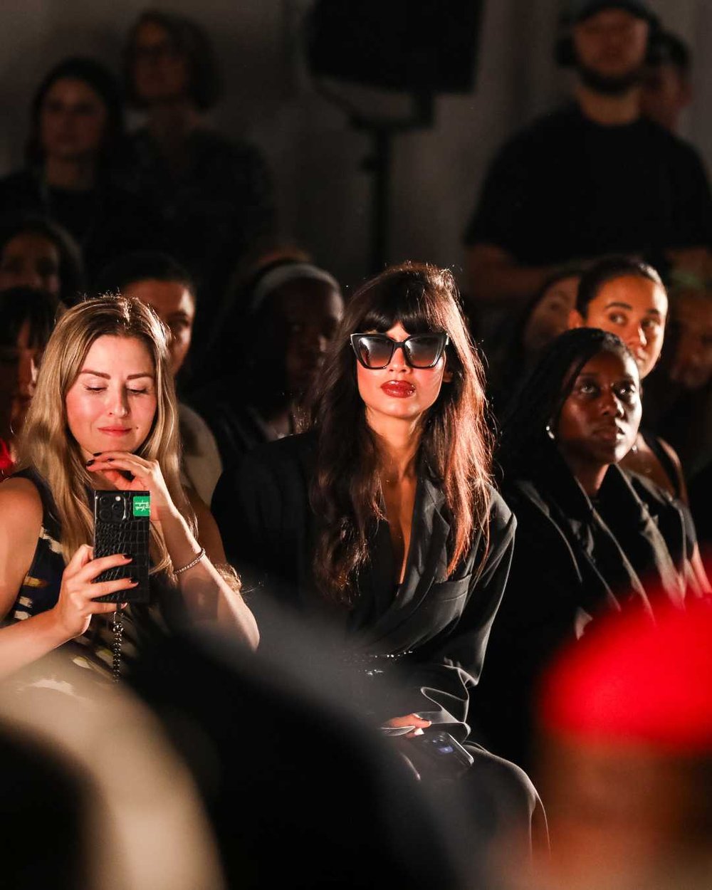Jameela Jamil sat front row at the Oxfam x Vinted Style for Change fashion show. She wears a black oversized blazer and sunglasses as she watches the show.