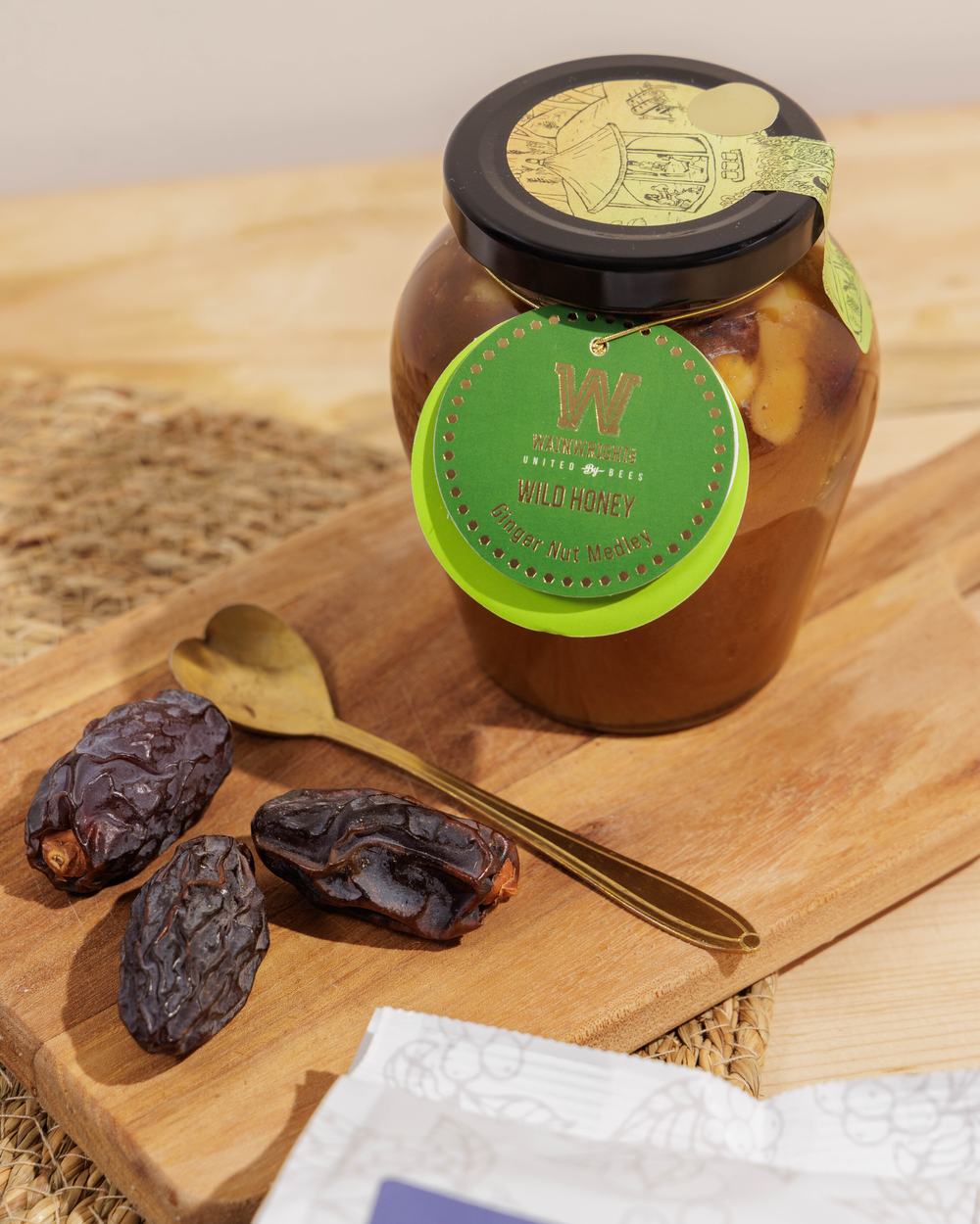 Wainwrights Honey on top a wooden board with three edible dates