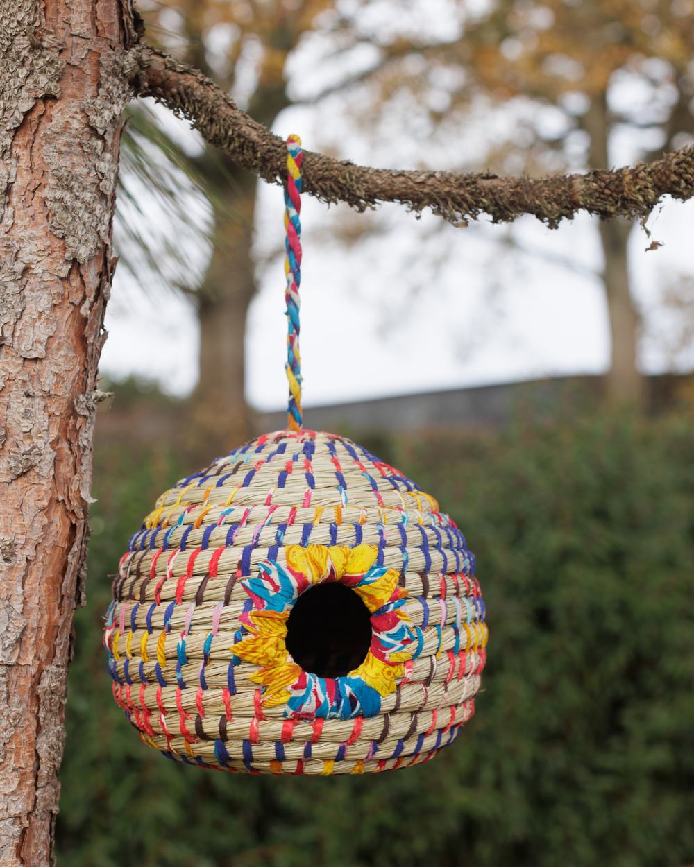 A spherical bird house made from recycled sari material
