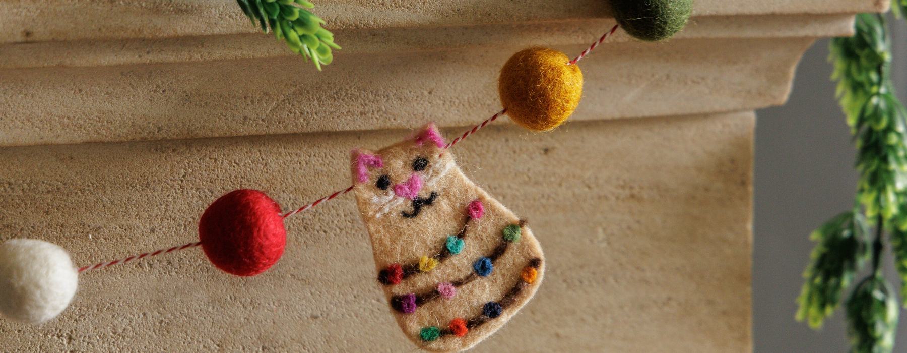 festive cat and pompom decoration on white mantelpiece