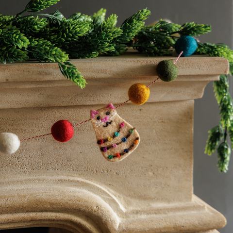festive cat and pompom decoration on white mantelpiece
