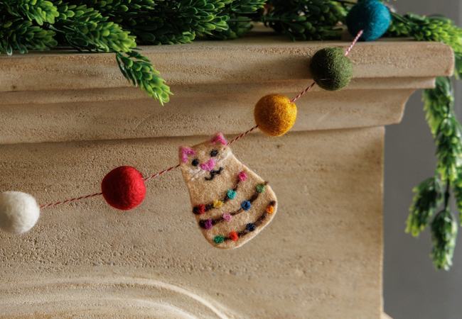 festive cat and pompom decoration on white mantelpiece