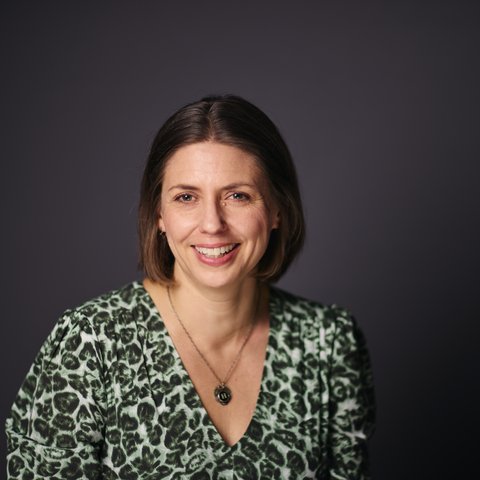 Woman with brown hair wearing a v-necked top and a necklace