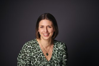 Woman with brown hair wearing a v-necked top and a necklace