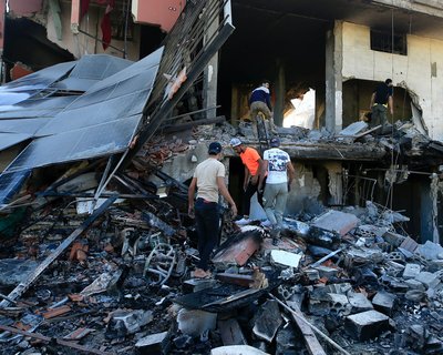 Five people searching through the remains of a bombed out building in Lebanon.