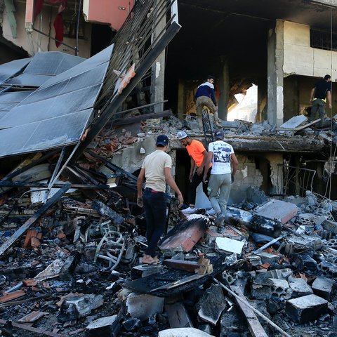 Five people searching through the remains of a bombed out building in Lebanon.