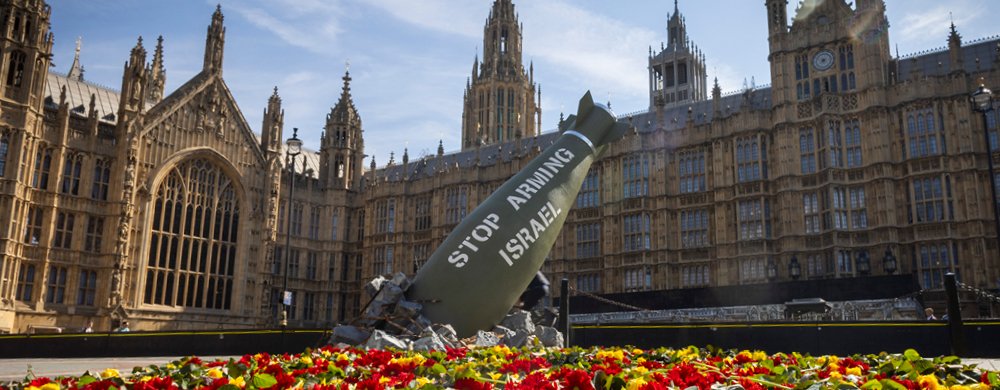 Replica bomb and flowers placed outside UK Parliament for an Oxfam media stunt.