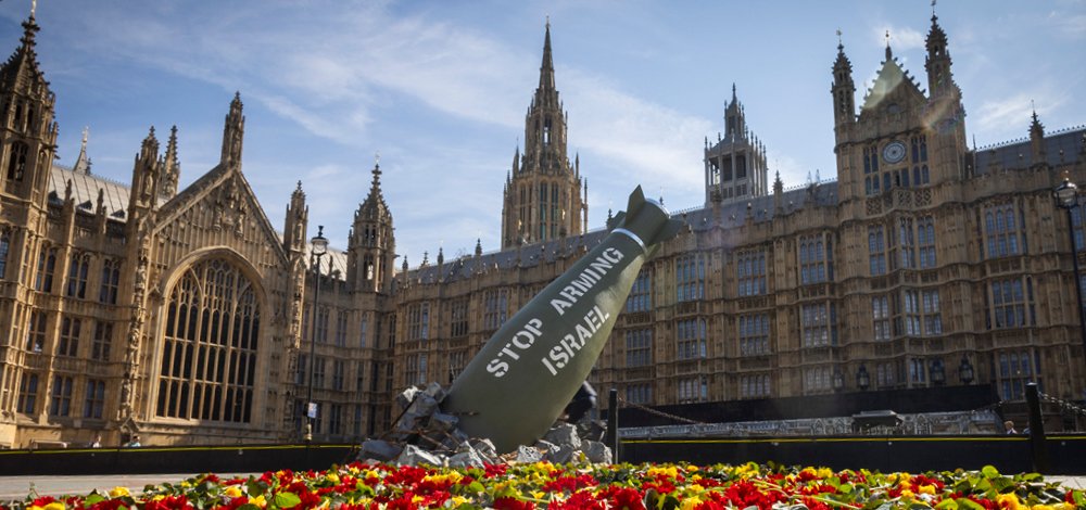 Replica bomb and flowers placed outside UK Parliament for an Oxfam media stunt.
