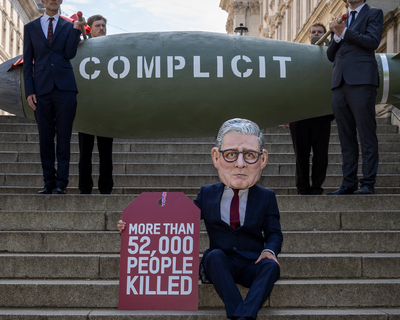 Oxfam’s ‘Keir Starmer’ Big Head appeared outside the UK Parliament placing a gift tag reading “More than 52,000 people killed” on a 16-foot replica MK-84 bomb marked “Complicit” on 12 May 2025, in London United Kingdom.