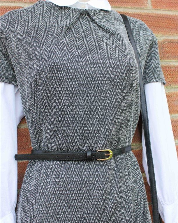 A grey dress with a narrow black belt around the waist