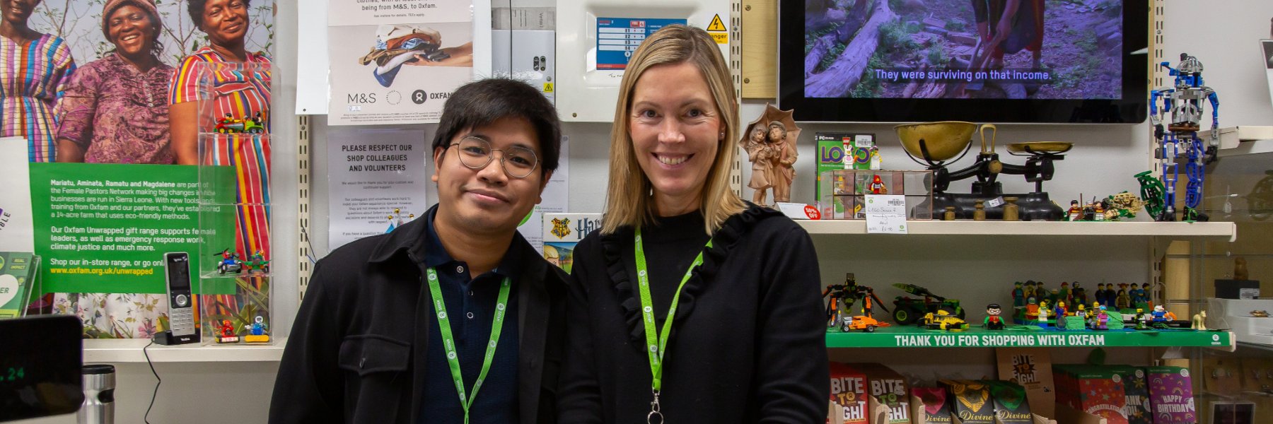 Smiling volunteers standing at the till in an Oxfam Shop