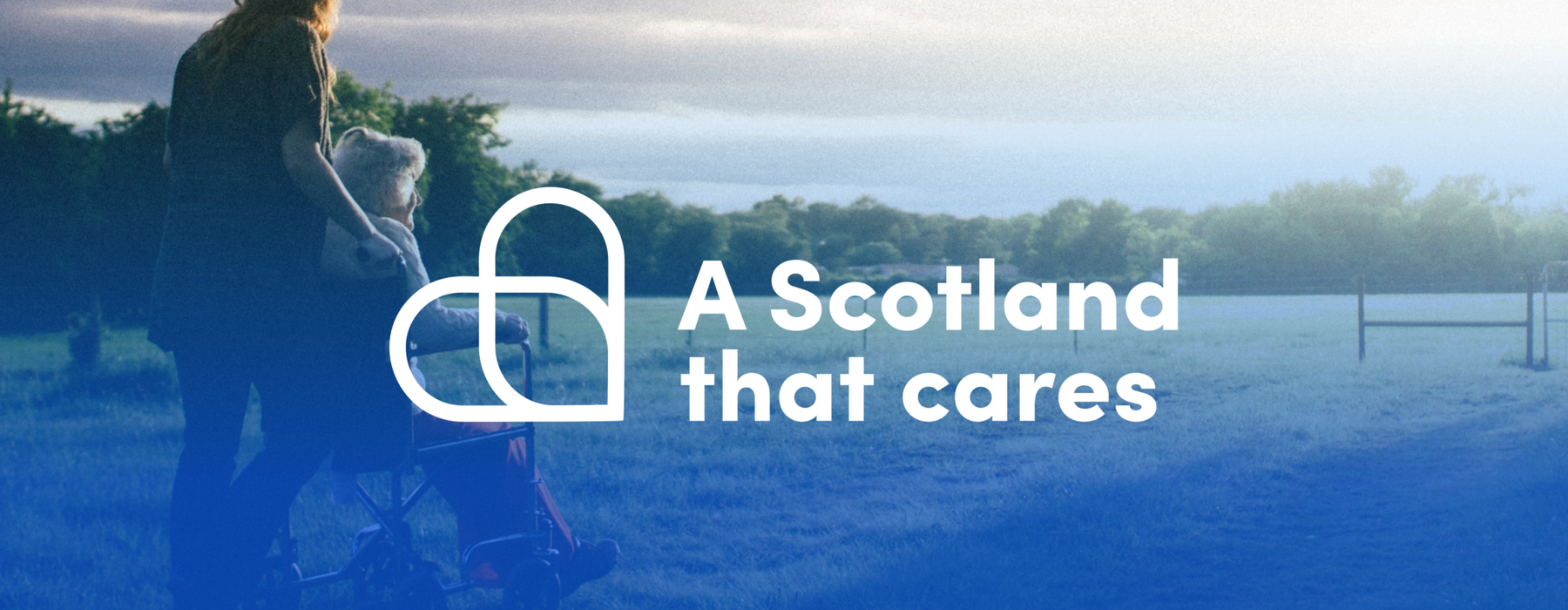 A woman pushing a white haired woman in a wheelchair. Text reads 'A Scotland that cares'