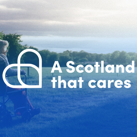 A woman pushing a white haired woman in a wheelchair. Text reads 'A Scotland that cares'