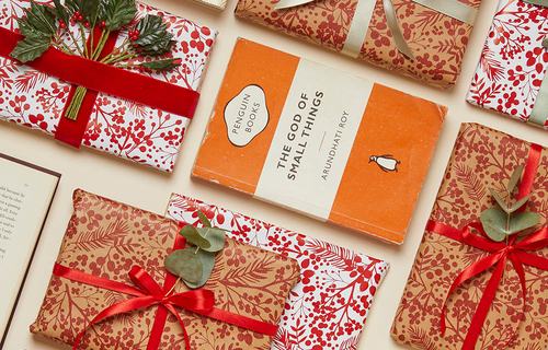 Books and wrapped Christmas gifts arranged with festive red and gold wrapping paper.