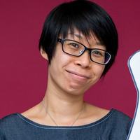 Head-and-shoulders portrait of a person with short dark hair and glasses in front of a dark pink backdrop.