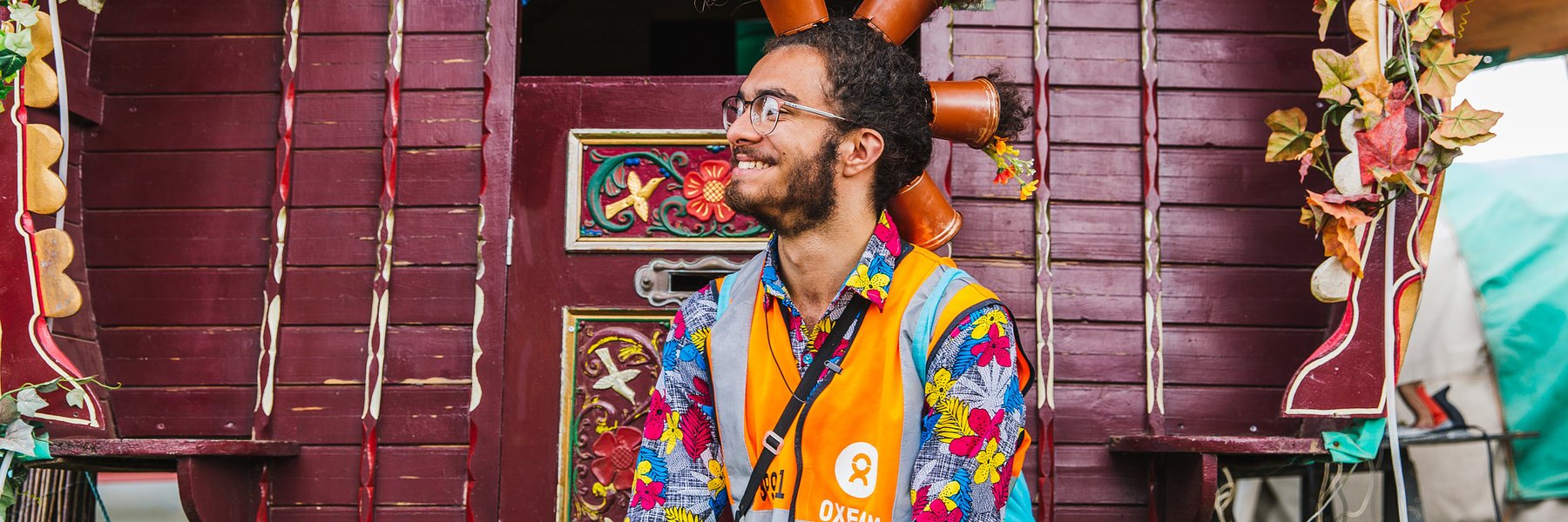 Smiling Oxfam festival steward at Shambala wearing flowerpots in hair