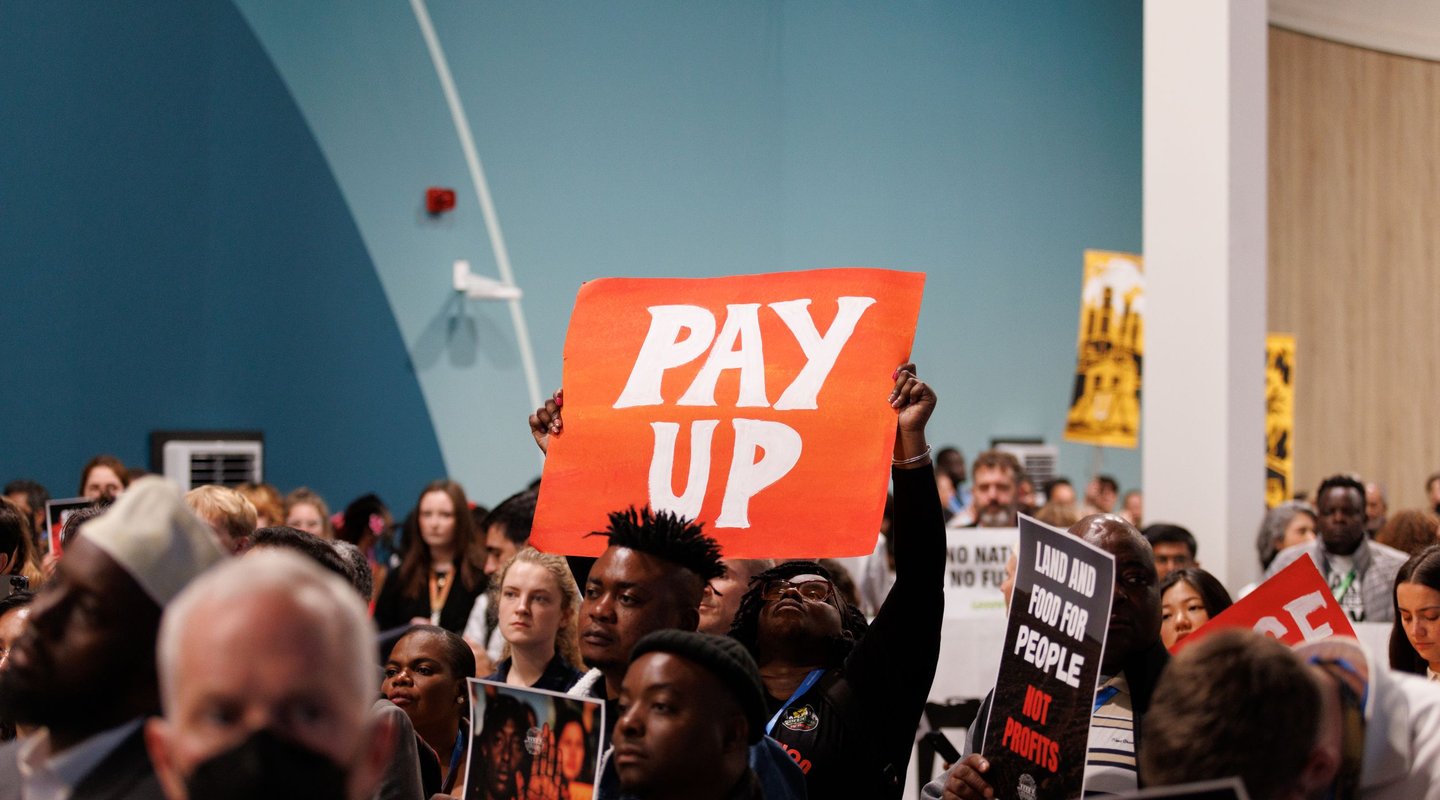 Campaigner holds 'Pay Up' banner at COP protest