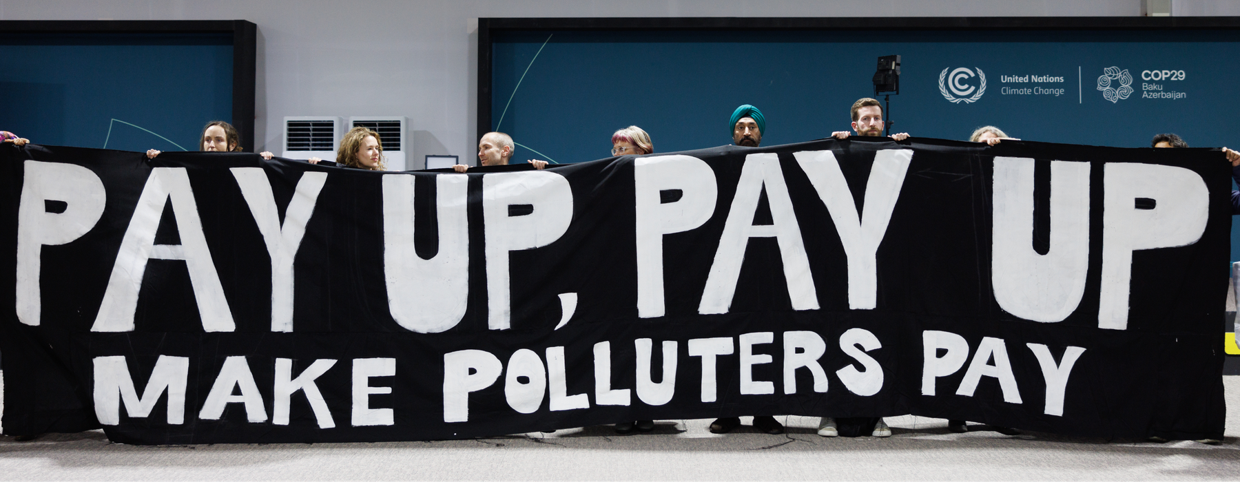 Activists are holding a giant banner at COP29 that says 'Pay up, Pay up, Make polluters pay'