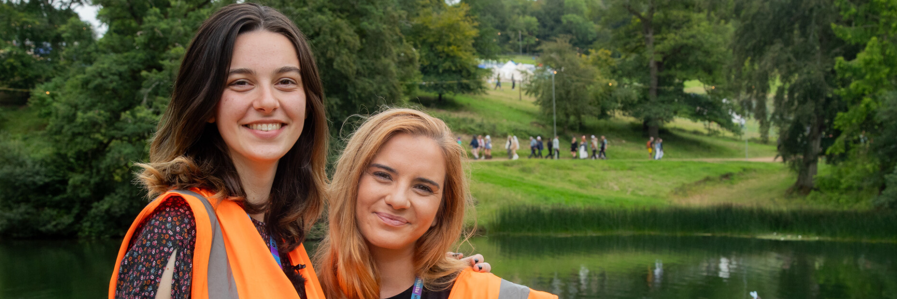 Gwen and Lauren smiling in front of a lake at Wilderness Festival