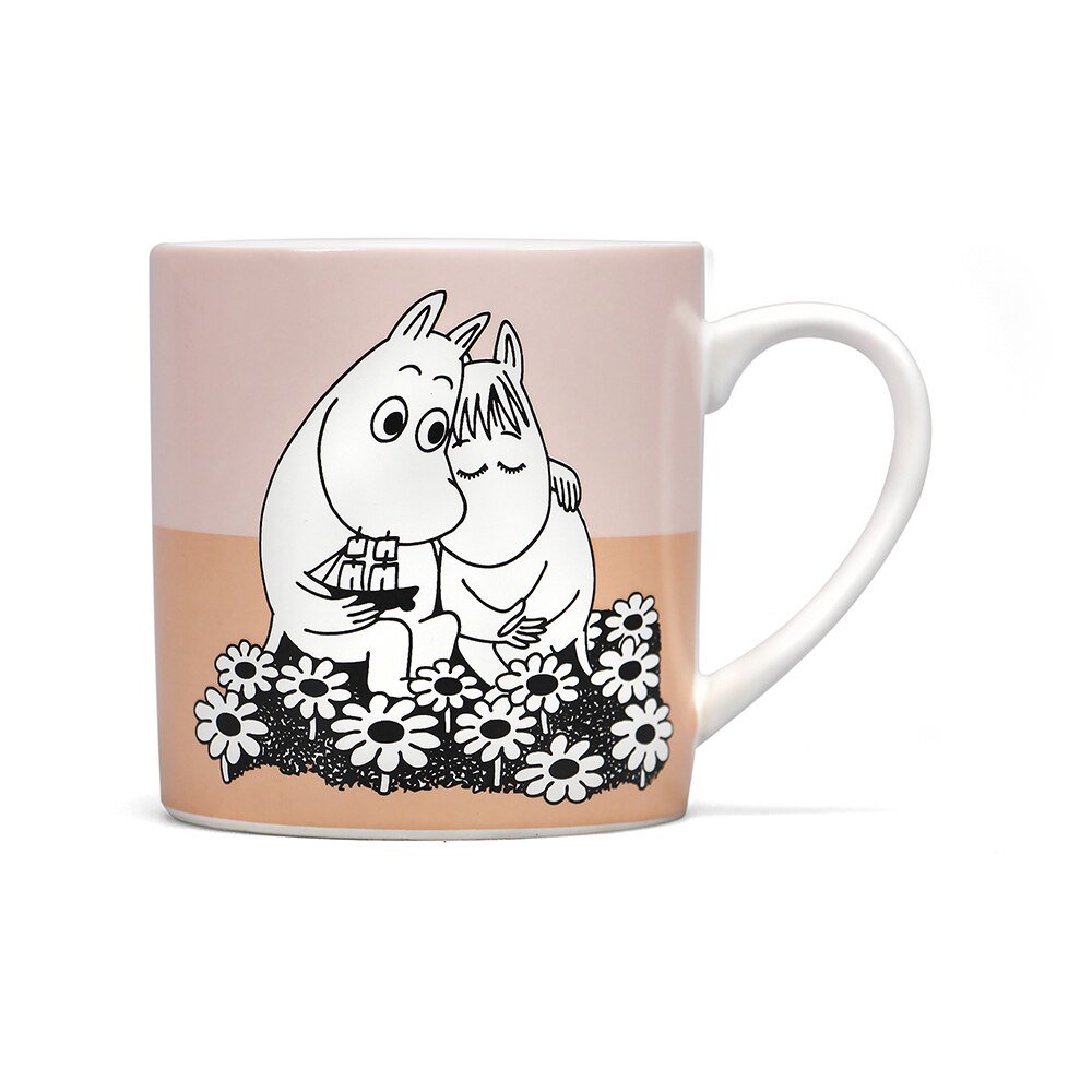 A pink and pale orange mug with black and white moomins hugging in a flower patch and one holding a toy ship