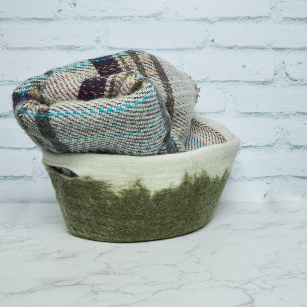 Felt green basket with blanket against white background