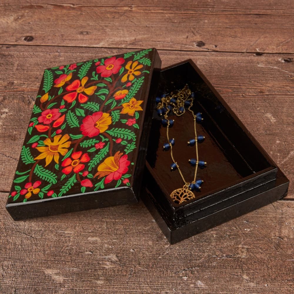 An open jewellery box with a necklace inside on a wooden table
