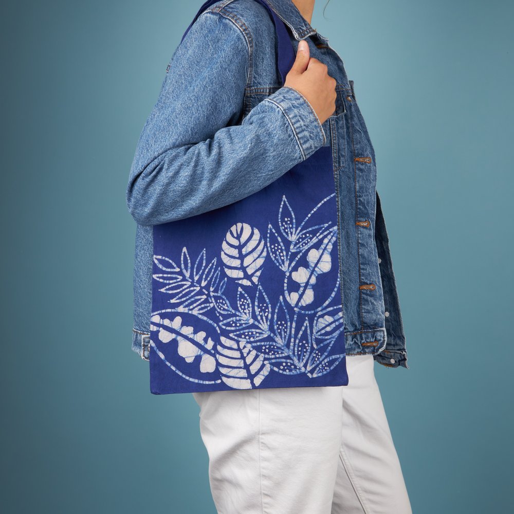person wearing blue tote bag with white floral print. They are standing in a photo studio