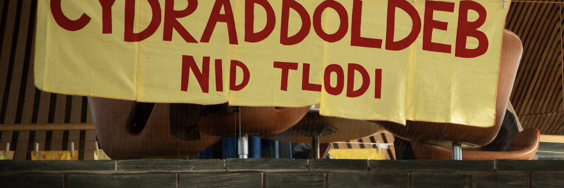 Llun o faner melyn gyda'r geiriau 'Cydraddoldeb nid Tlodi' arni