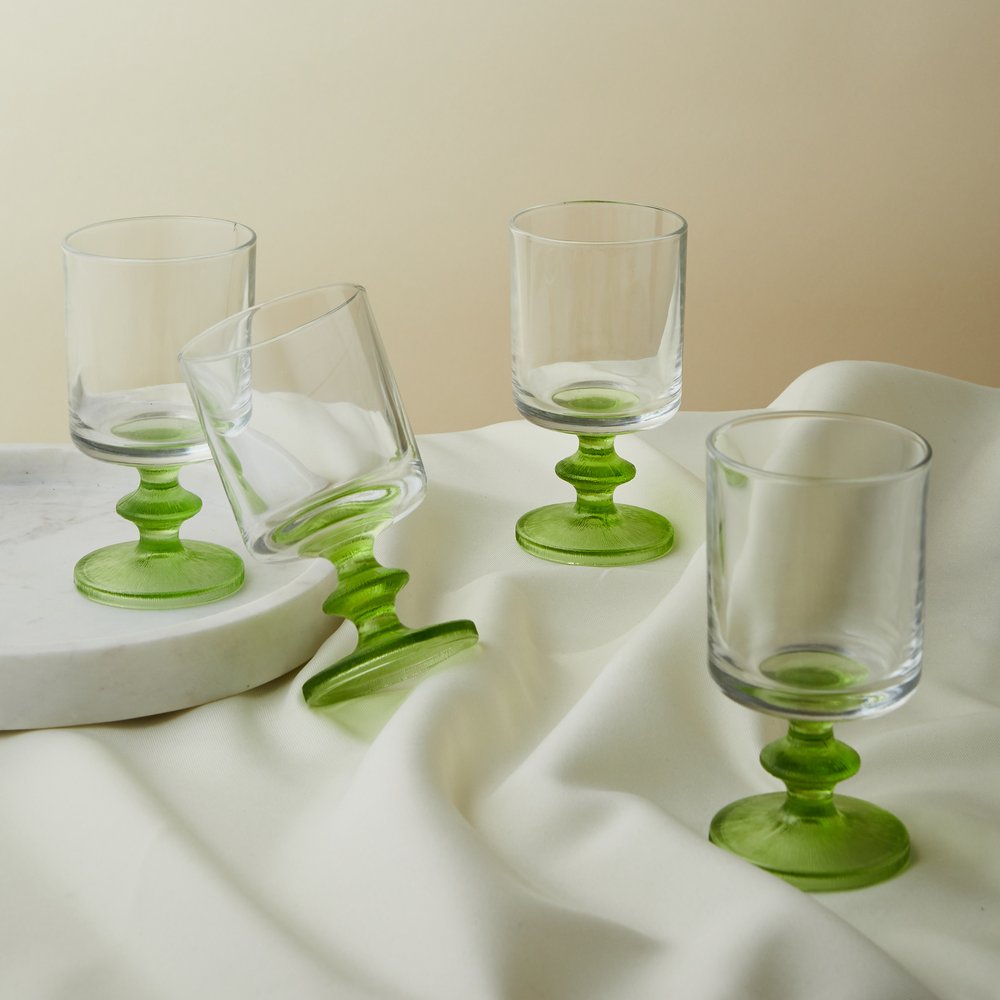 Green stemmed wine glasses laid on white fabric