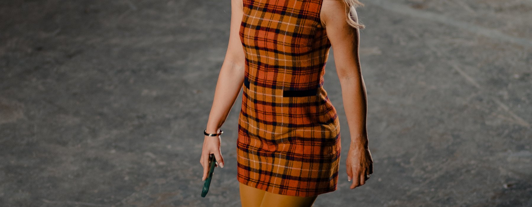 Katie Piper walking the catwalk at the Oxfam x Vinted Style for Change fashion show. She wears an orange checked mini dress, mustard tights and orange platform heels.