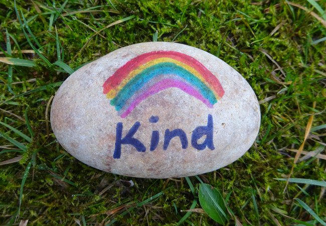 A pebble painted with a rainbow and the word 'Kind'.