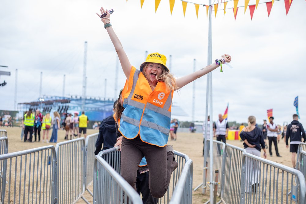 Oxfam Leeds steward volunteering on a gate and jumping in the air