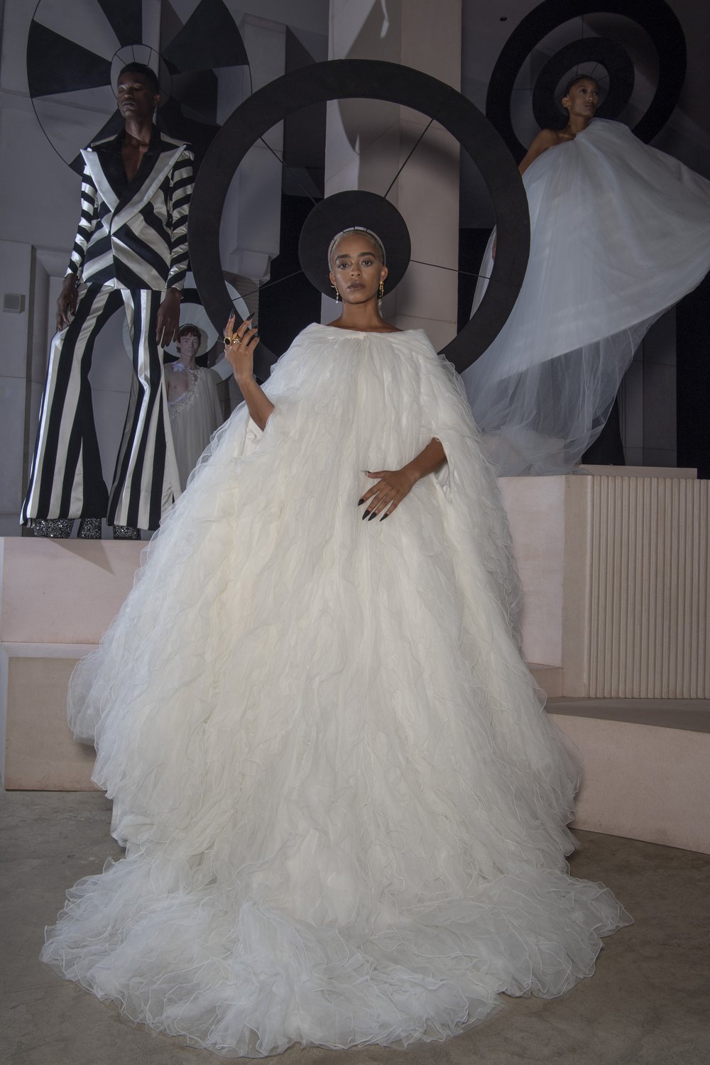 A model wears a demi-couture bridal gown made from Oxfam pre-loved bridal wear and a black halo.