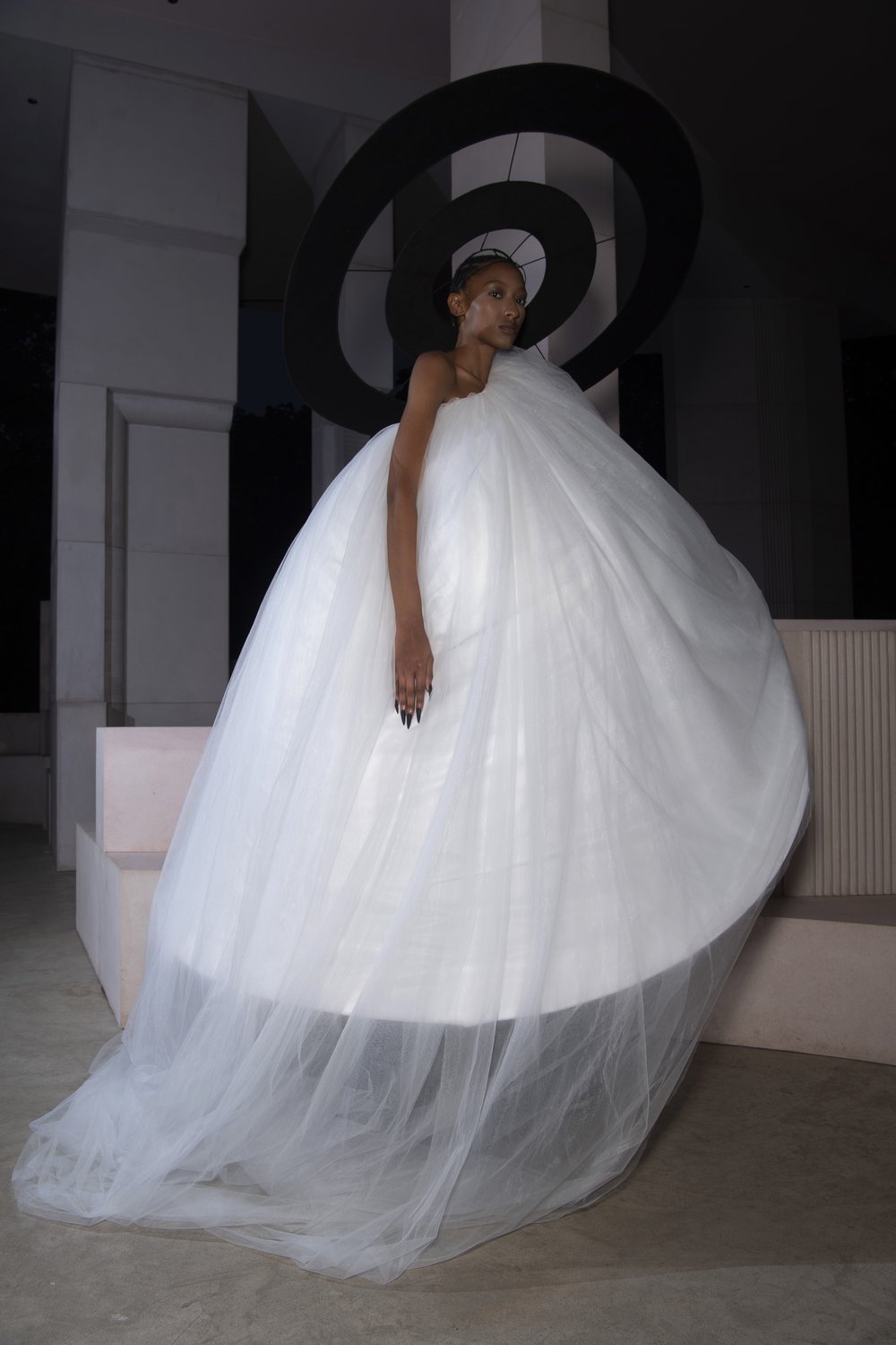 A model wears a demi-couture bridal gown made from Oxfam pre-loved bridal wear and a black halo.