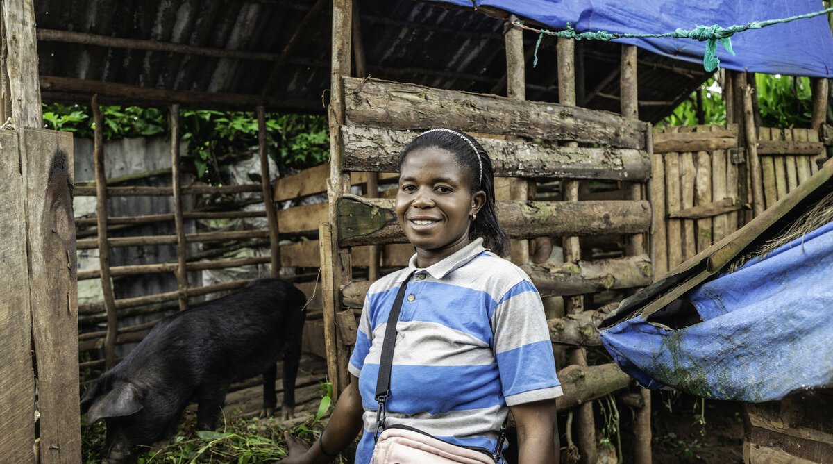 Marie Nsimire stands next to her pigs.