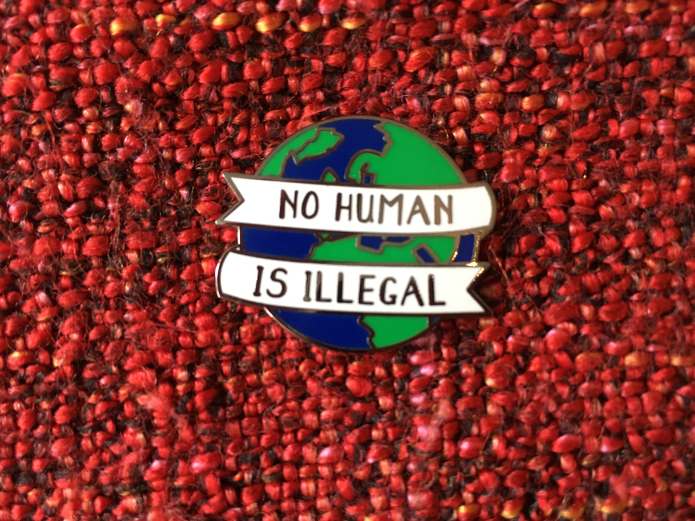 A badge with a picture of a globe that says 'no human is illegal'