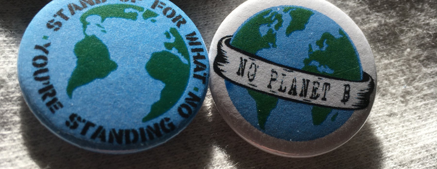 Two badges, one says 'stand up for what you're standing on' and the other says 'no planet b'