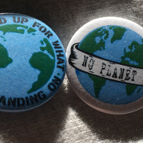 Two badges, one says 'stand up for what you're standing on' and the other says 'no planet b'