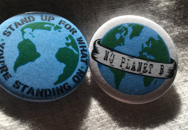 Two badges, one says 'stand up for what you're standing on' and the other says 'no planet b'