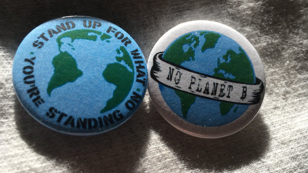 Two badges, one says 'stand up for what you're standing on' and the other says 'no planet b'